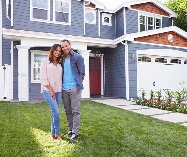 happy couple standing in front of new home