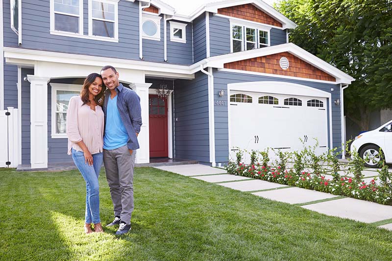 happy couple standing in front of new home