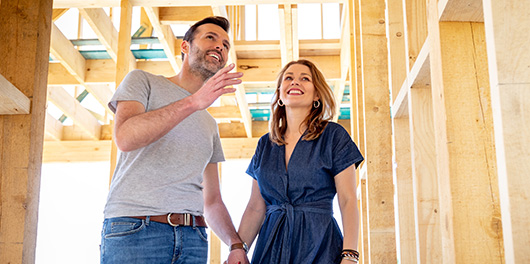 Man and woman walking through an unfinished building while smiling