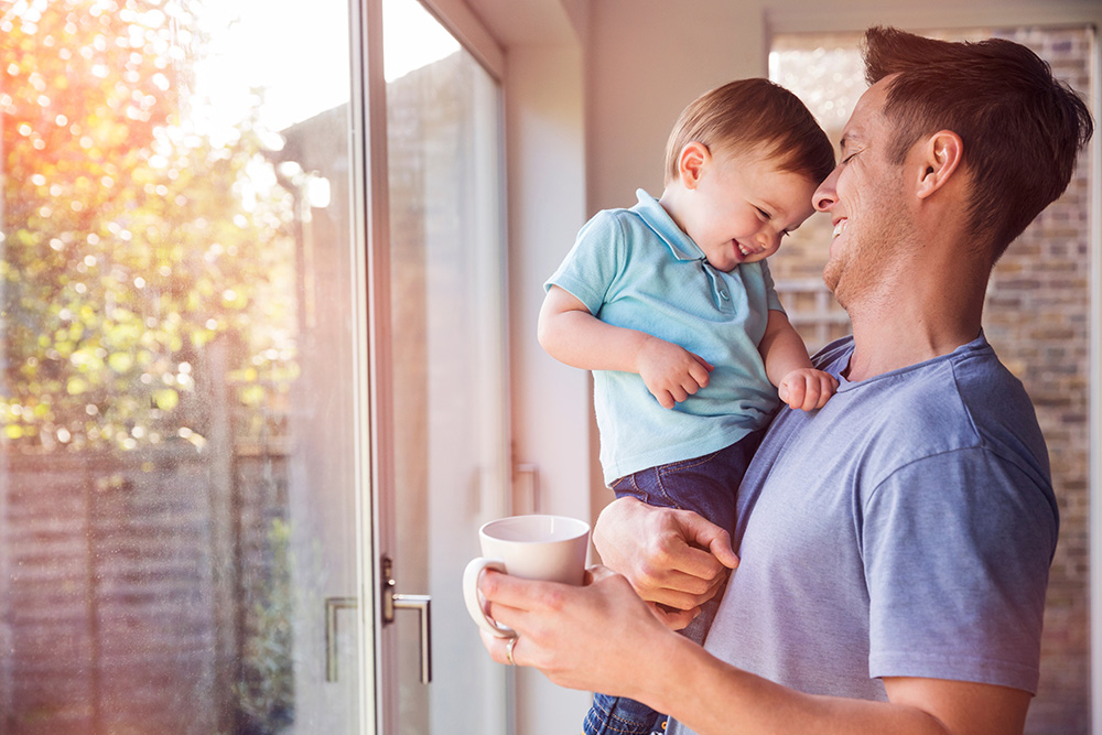 Dad holding son while sipping coffee