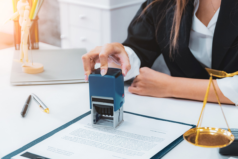Woman sits at table with a stamp on top of an official document