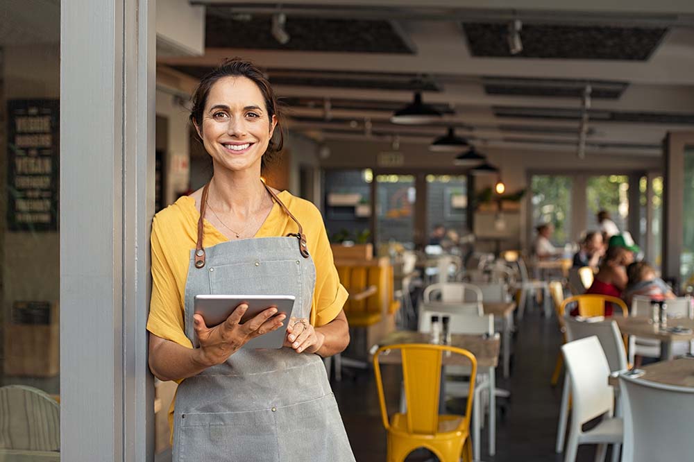 female business owner standing in business holding a tablet