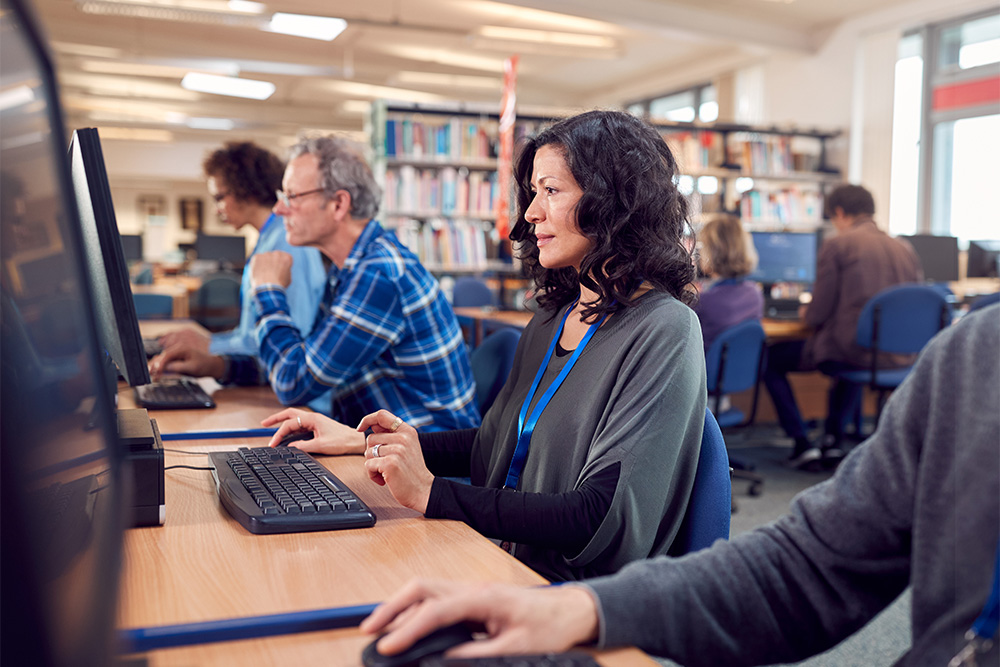 Woman with dark hair sits at a computer in the library