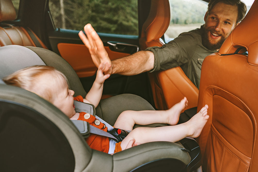Dad giving baby a high five from the front seat of the car 