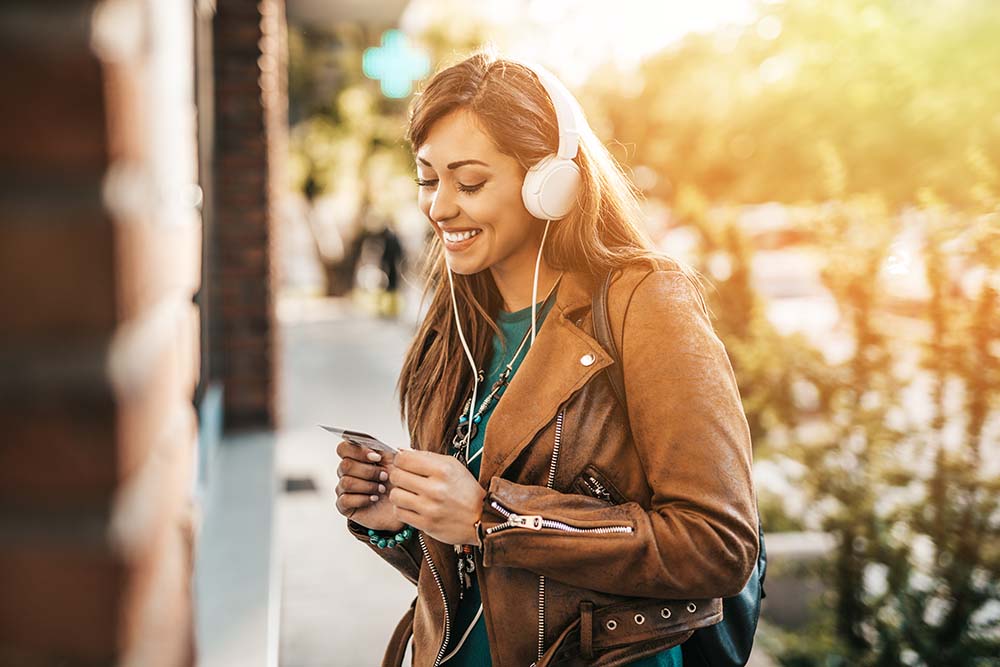 woman looking at credit card with headphones on outside