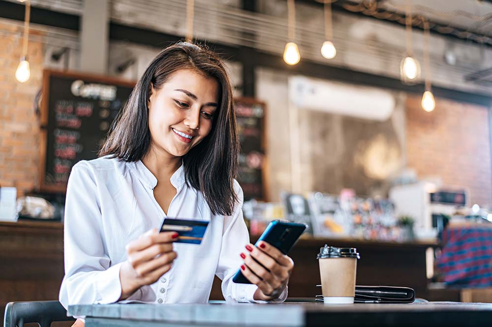 woman using mobile phone and credit card to make a purchase