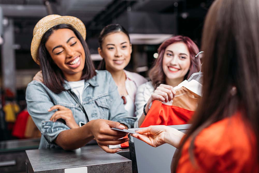 young woman and friends handing cashier credit card