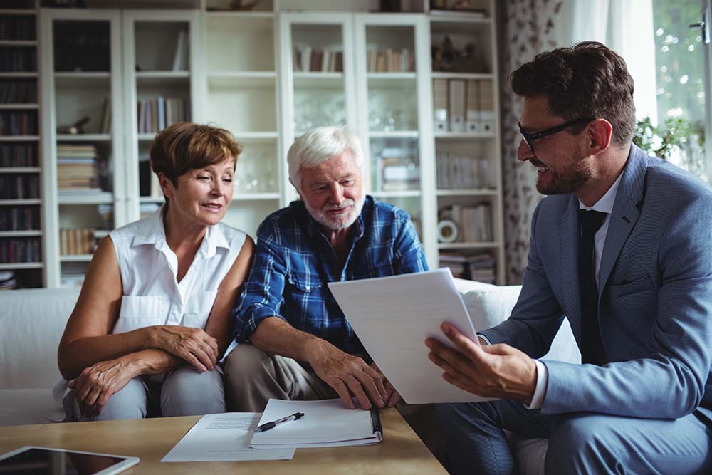 elderly couple reviewing financial documents with advisor