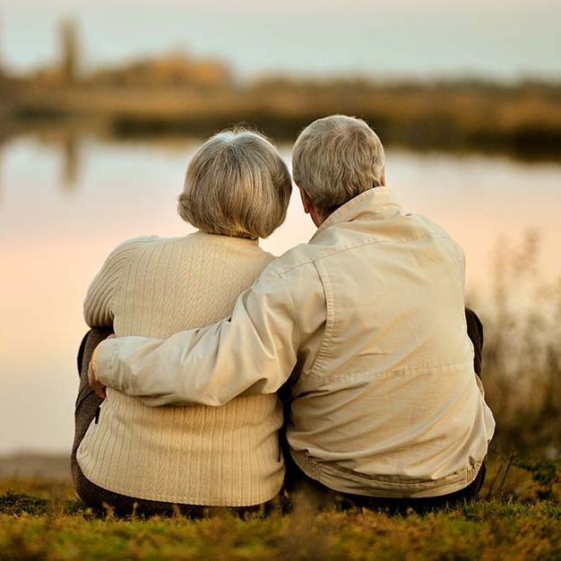 elderly couple looking over lakeside at sunset