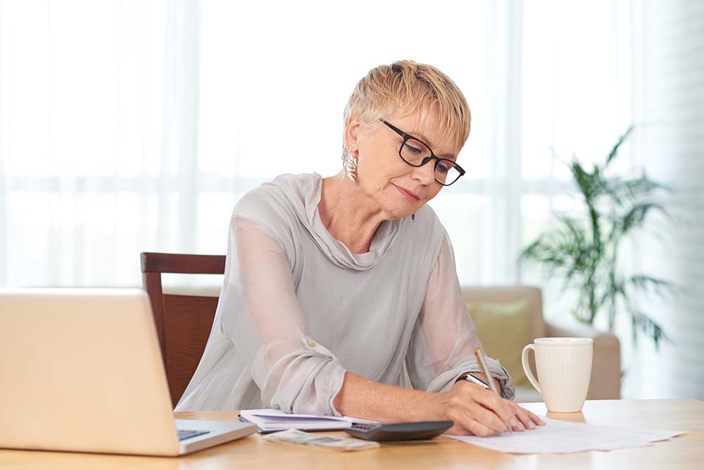 older woman working on documents while on computer
