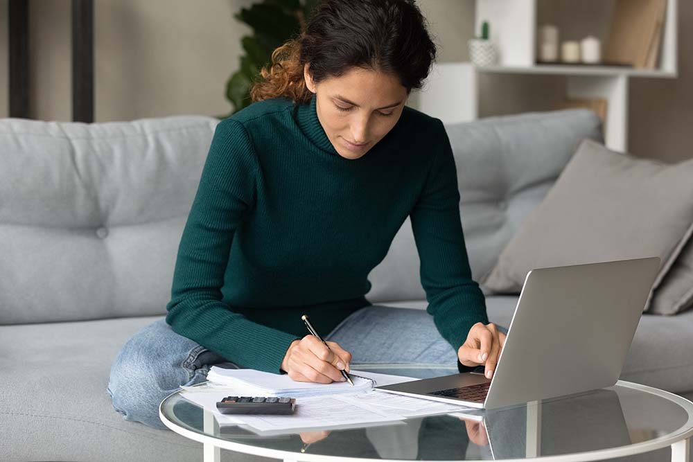 woman reviewing documents while working on laptop