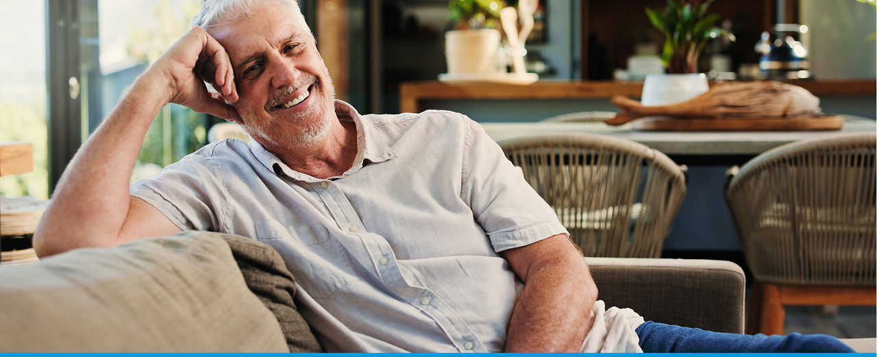A man sitting back on a couch and leaning on his arm