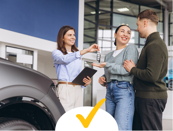A couple taking keys from a car saleswoman
