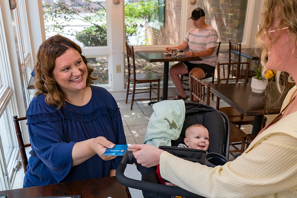 woman handing card to server at cafe