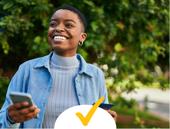 A young woman in blue holding a cell phone and smiling