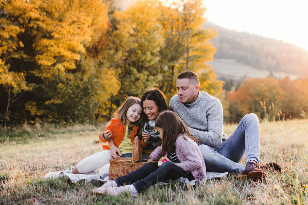 Family of four having a picnic in scenic fall mountains