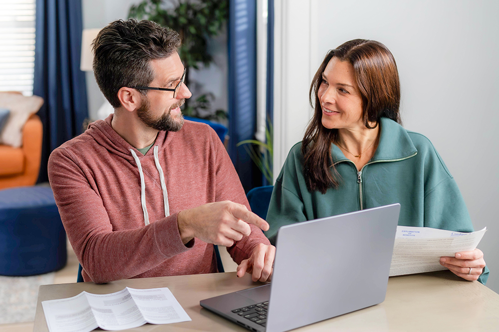 A man and woman sit at a table, looking at each other. 